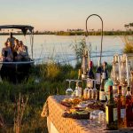 A boat on a lake approaches a table with drinks at Duma Tau