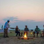 Ruckomechi camp guide telling stories around a fire to guests